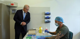 Prime Minister Scott Morrison looks on as pharmacist Branko Radojkovic prepares a simulation of the COVID-19 vaccine at Sydney's Royal Prince Alfred Hospital last week